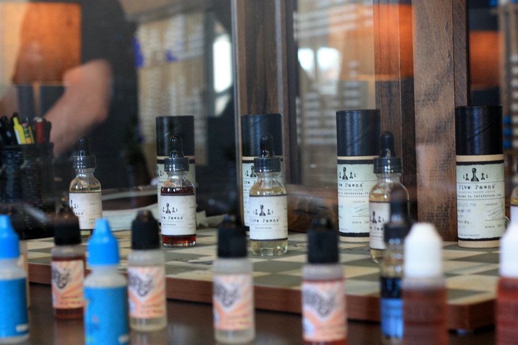 Rows of e-liquid bottles on a checkered counter in a vape shop